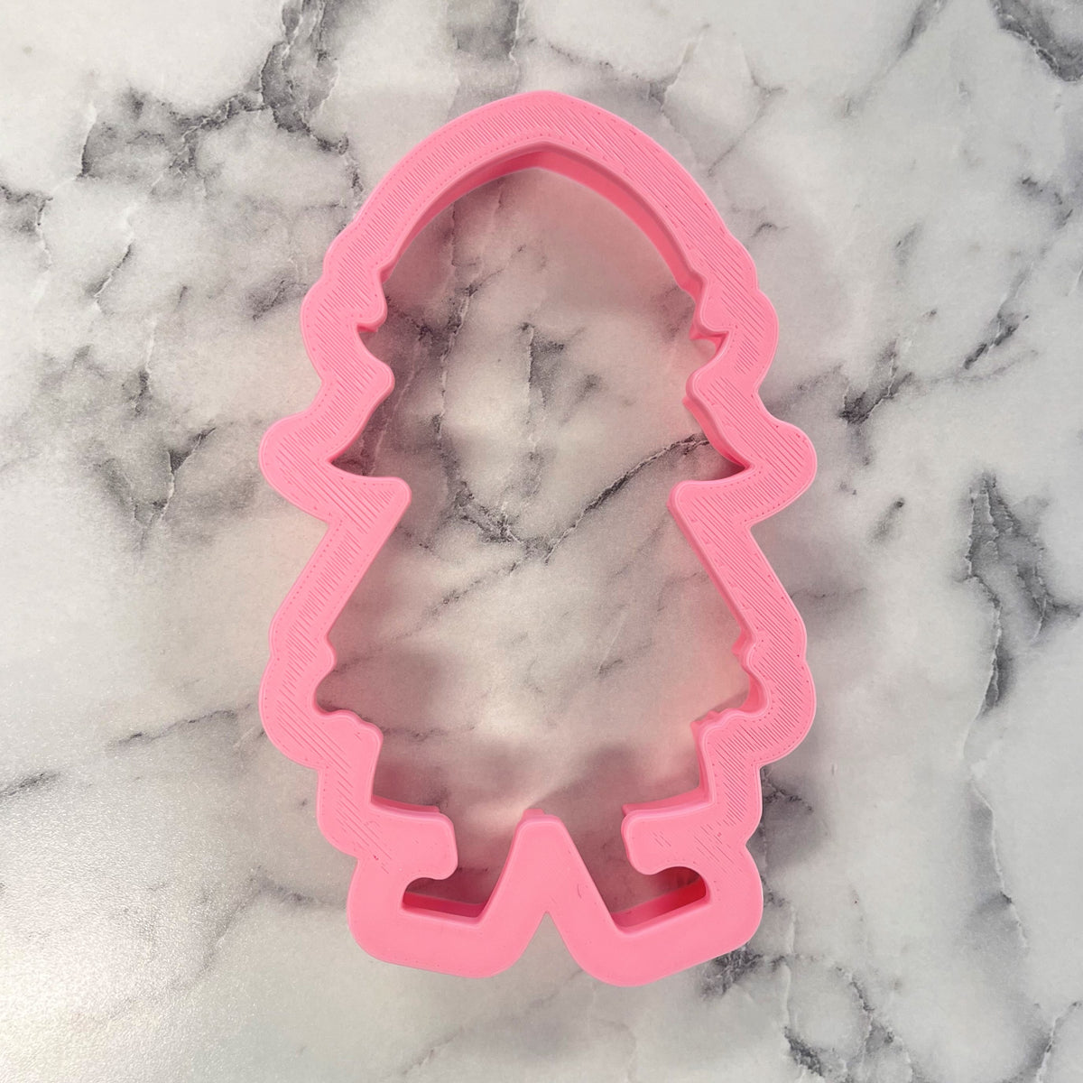 Pink plastic elf girl cookie cutter shaped like a cartoon girl with long wavy hair and a dress for baking