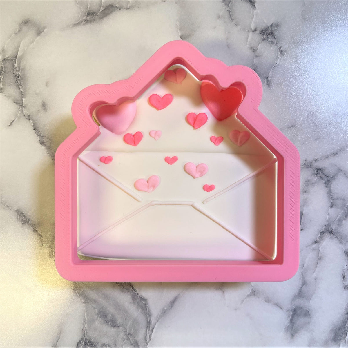 Pink silicone envelope cookie cutter with clear window and heart decorations for baking and crafting