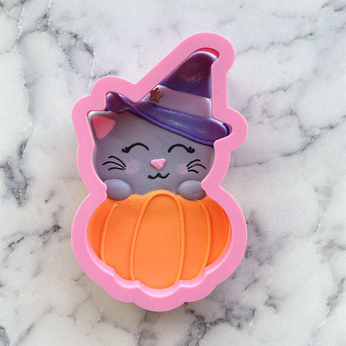 Pink silicone fab-boo-lous cat in pumpkin cookie cutter with purple glitter witch hat and orange segmented pumpkin design