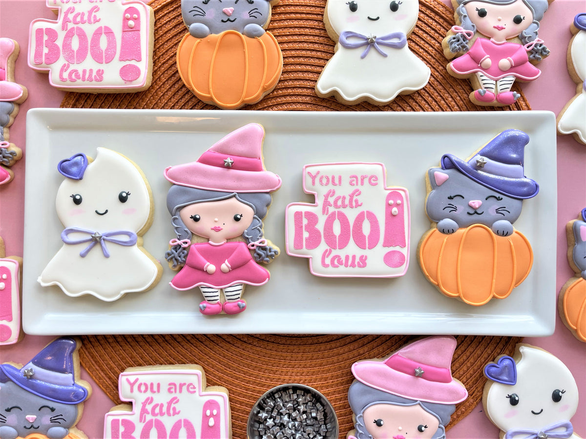A pink witch cookie with a star-adorned hat and striped leggings from the fab-boo-lous cookie cutter bundle with stencil