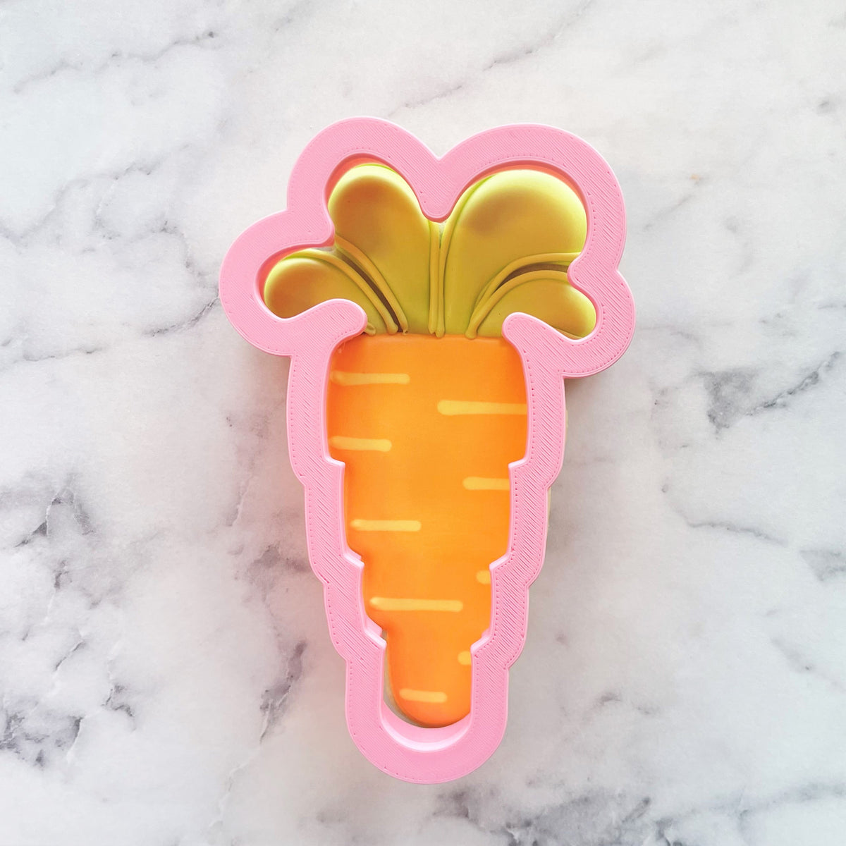 Floppy carrot cookie cutter in pink and orange with a yellow leafy top for fun carrot-shaped cookies
