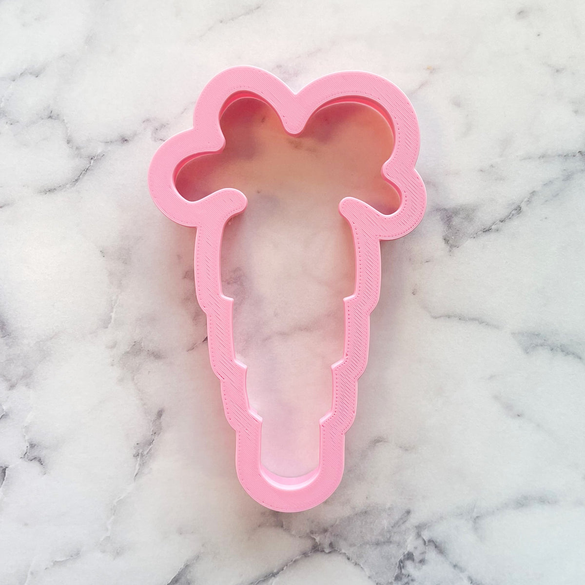Pink plastic floppy carrot cookie cutter designed for shaping carrot-themed cookies and treats