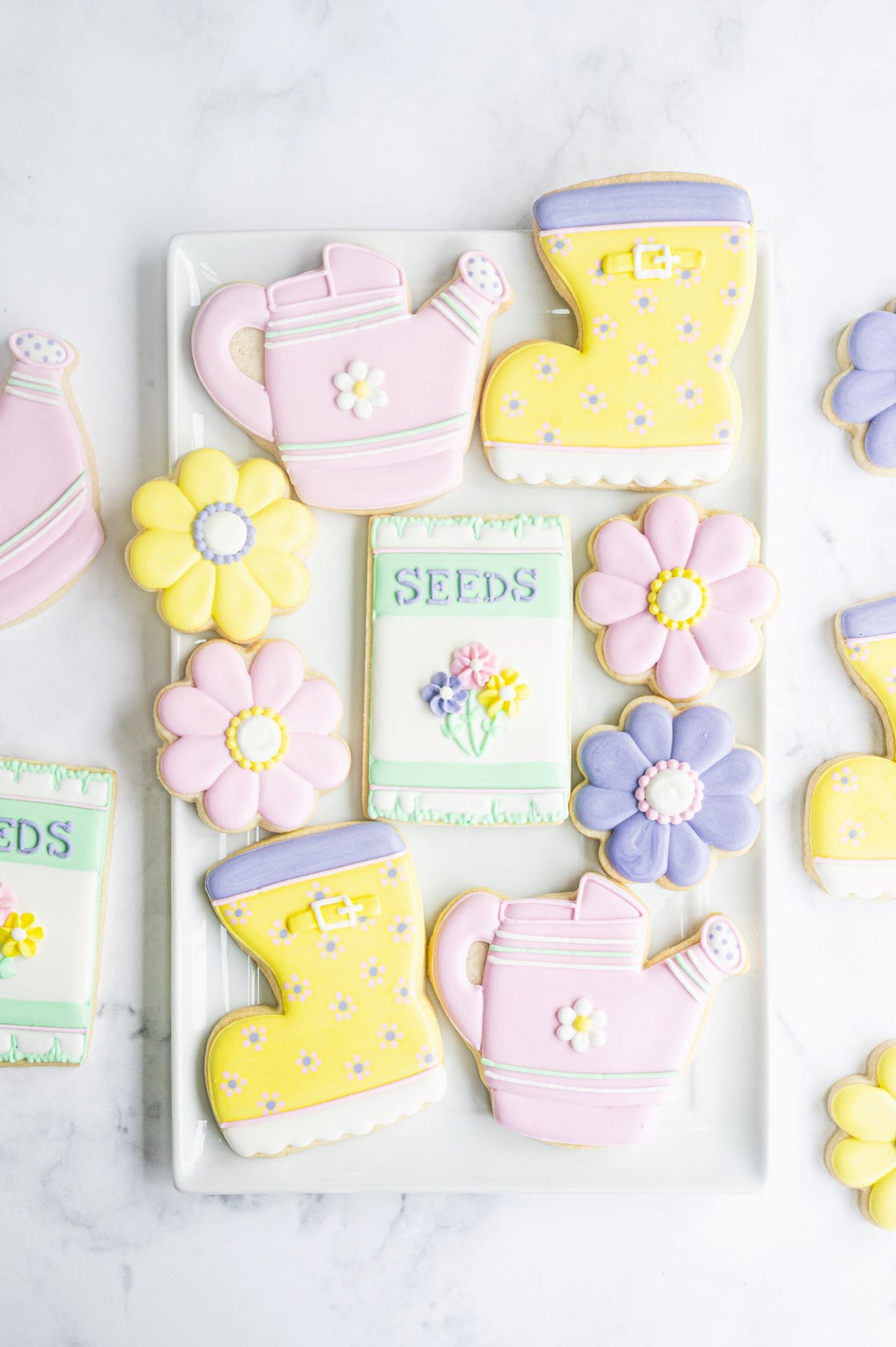 Pastel pink and yellow sugar cookies shaped like garden tools and flowers with delicate icing by Anne Yorks
