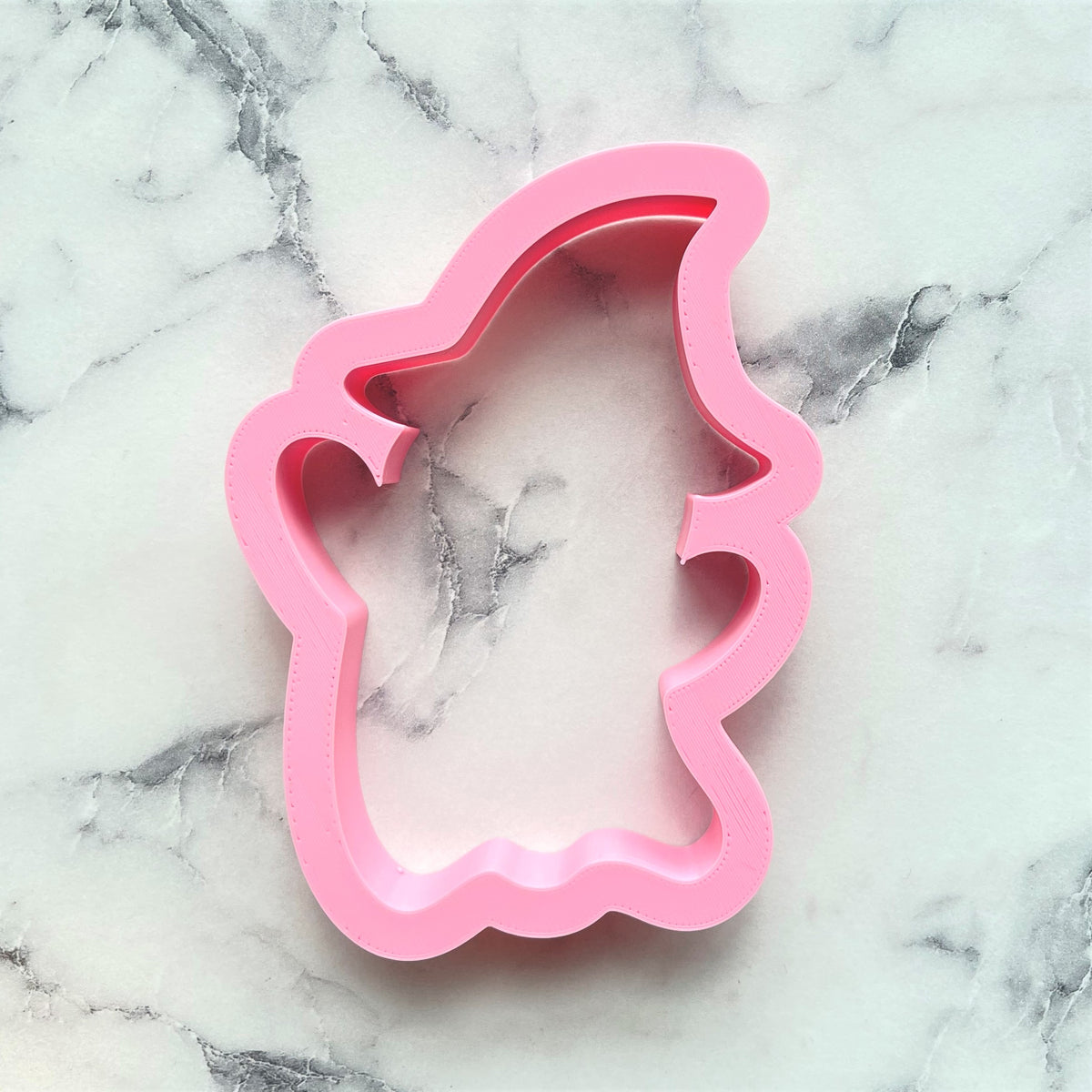 Pink silicone ghost with hat cookie cutter for baking shaped like a ghost wearing a hat