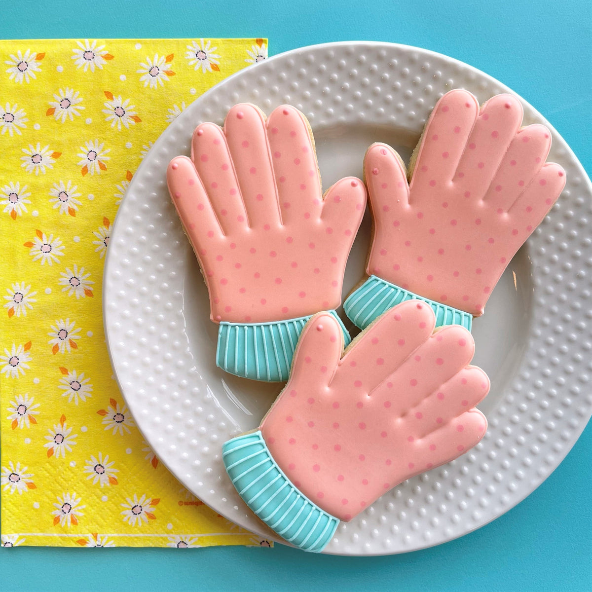 Pink and teal polka dot sugar cookies shaped like gloves made with a garden glove cookie cutter