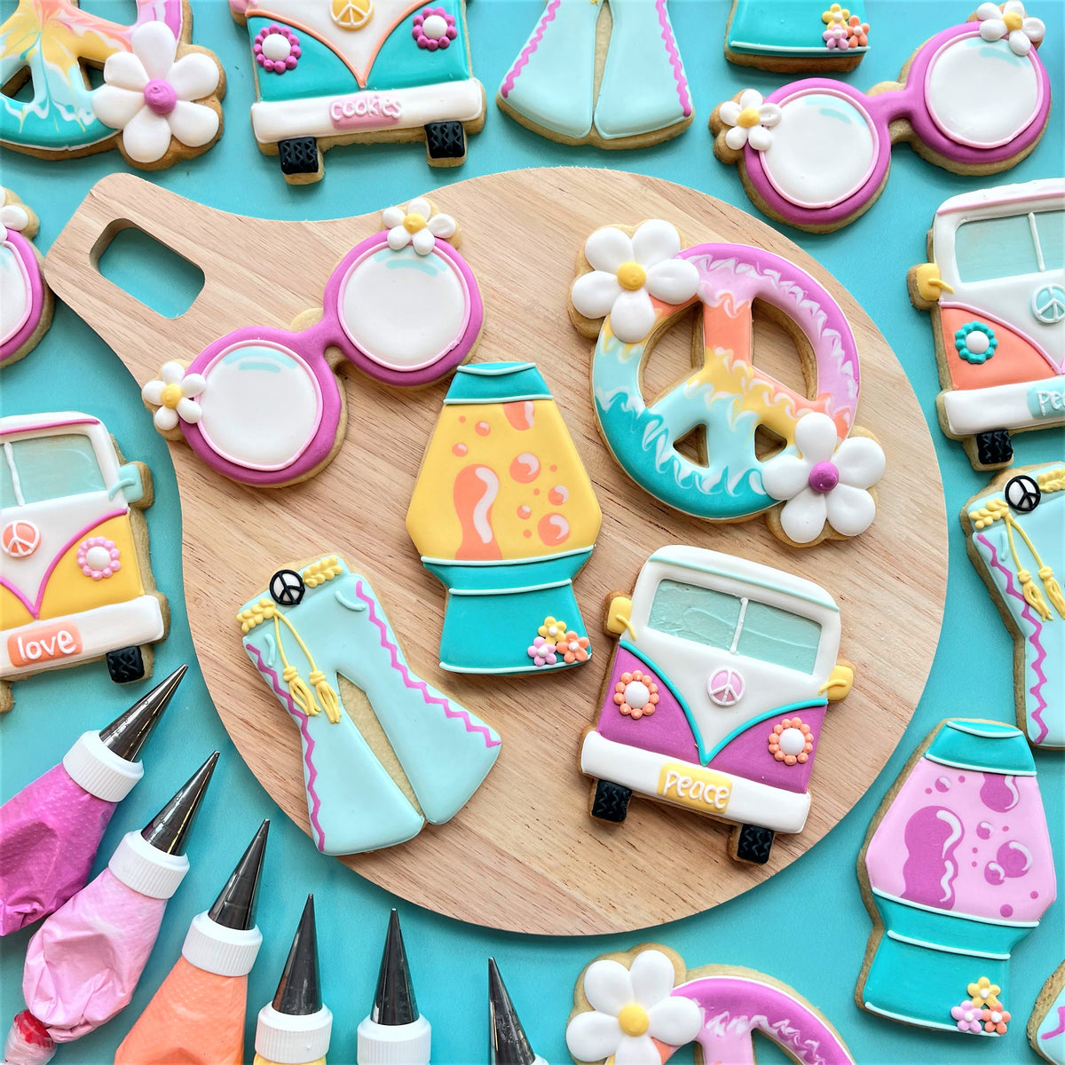 Pastel pink and teal peace sign cookie decorated with white flowers made using a groovy sunglasses cookie cutter
