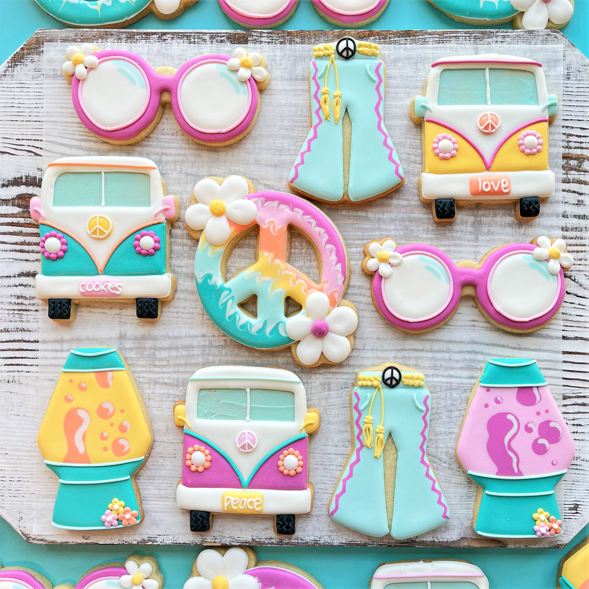 Pastel-colored sugar cookies shaped like vintage volkswagen vans with peace signs and floral decorations from groovy 5 cutter bundle and digital decorating guide