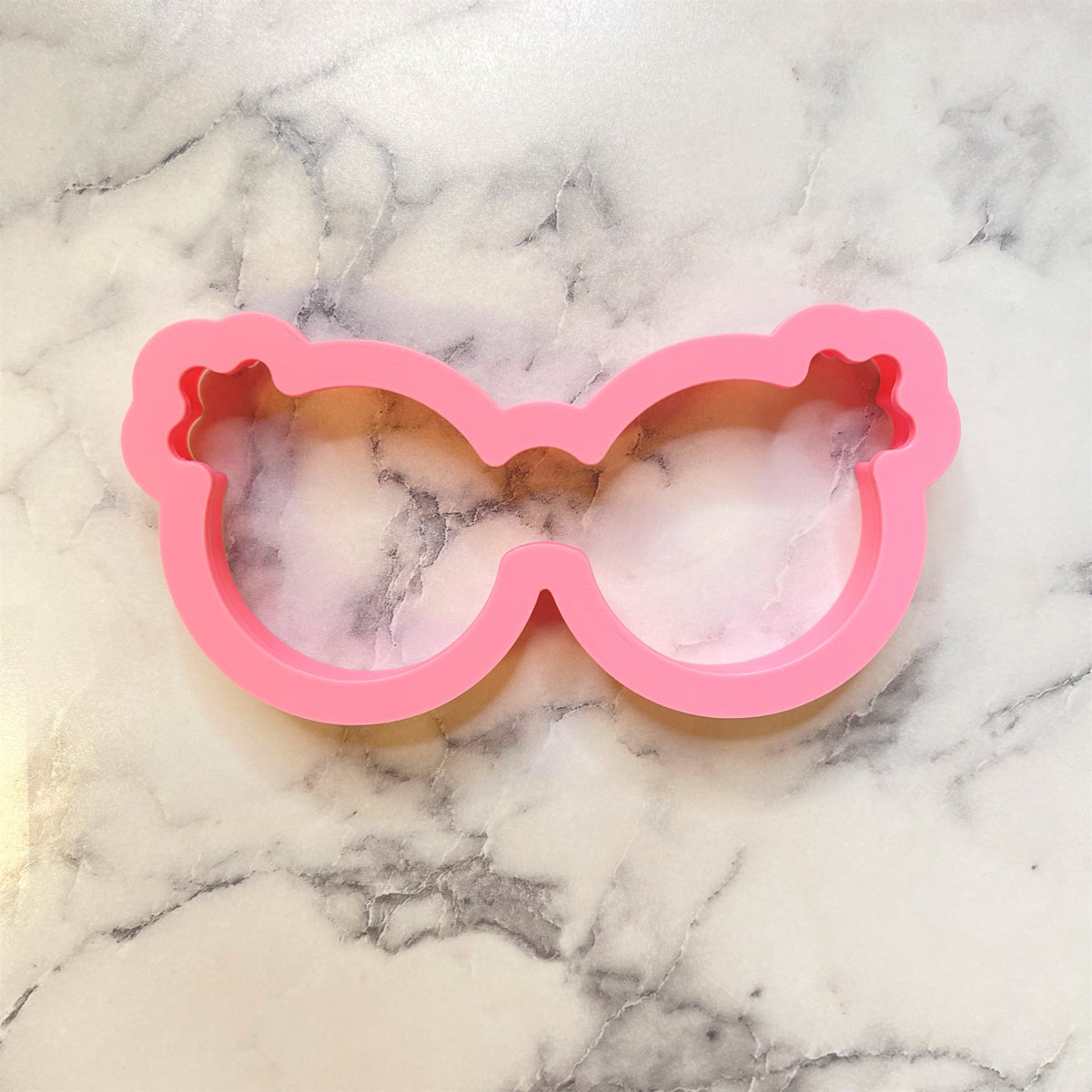 Pink silicone groovy sunglasses cookie cutter shaped like oversized sunglasses for fun baking designs