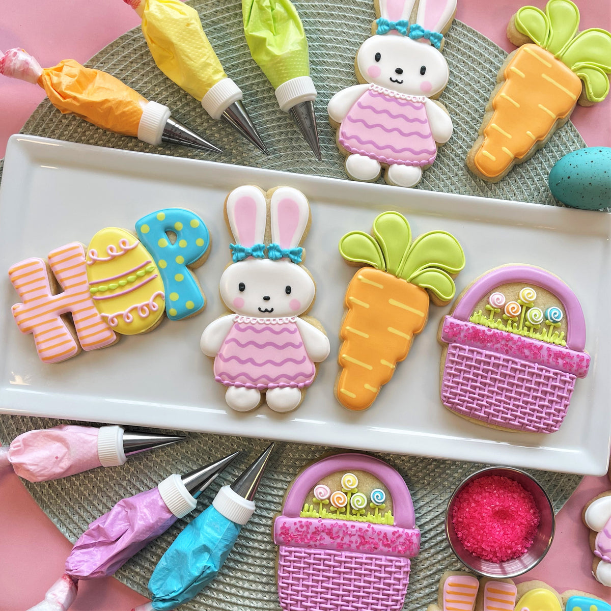 Pastel pink and white sugar cookie bunnies with blue bows and striped dresses from hop easter cookie decorating class recording