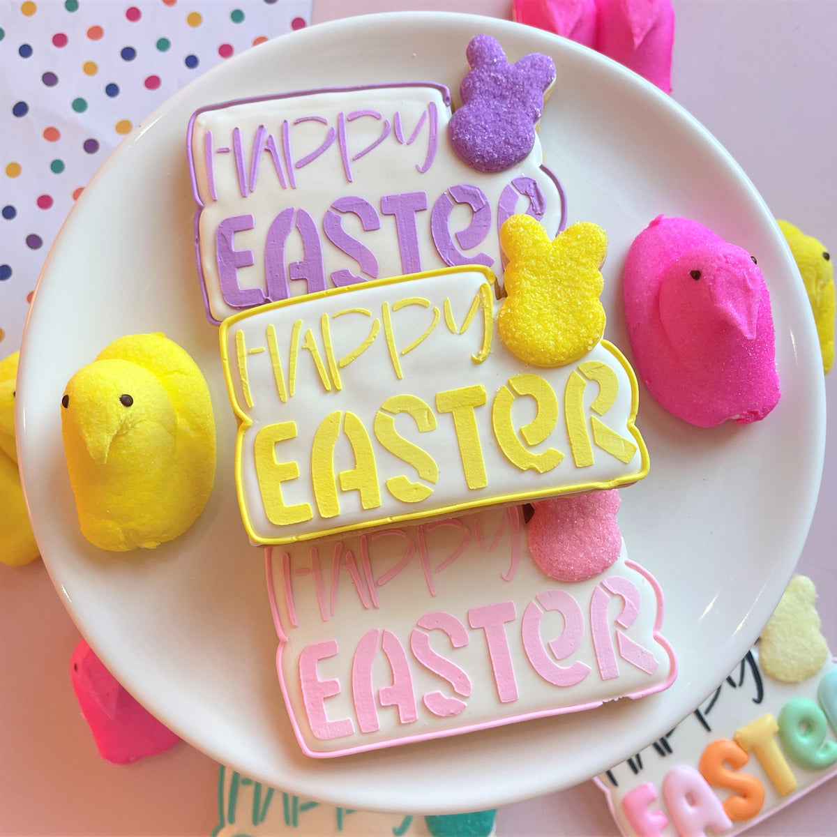 Pastel-colored happy easter cookies with icing and marshmallow chicks made using happy easter plaque cookie cutter with stencil