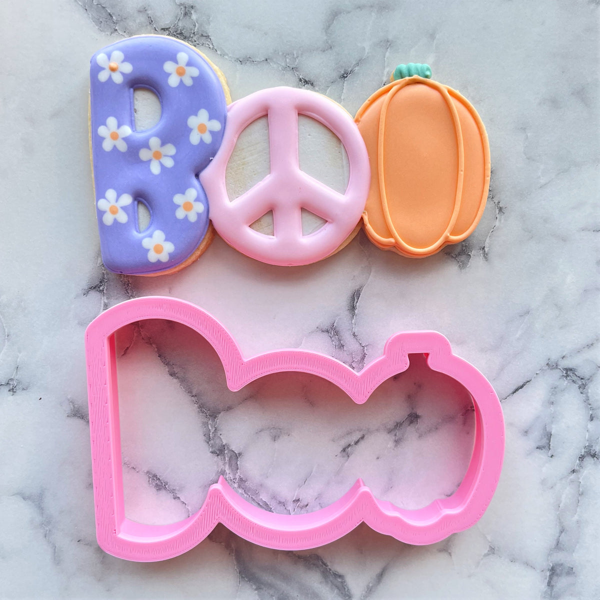 Pink plastic boo cookie cutter with peace sign and pumpkin design for halloween baking and decorating