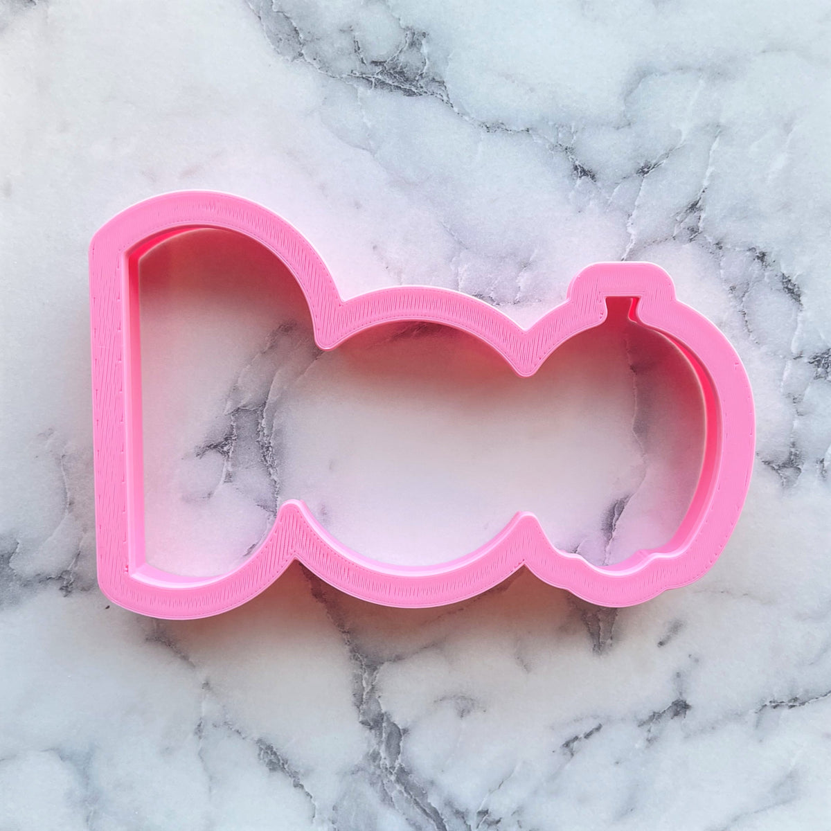 Pink plastic boo cookie cutter shaped like a bow tie for baking and decorating treats