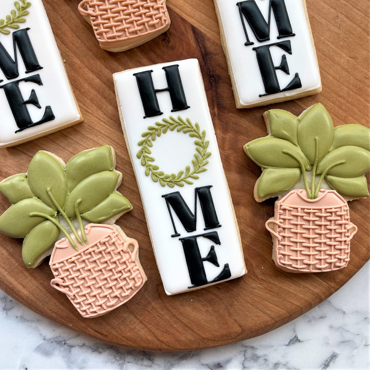 White rectangular cookie with black home lettering and green leaf wreath made using rectangle tall cookie cutter
