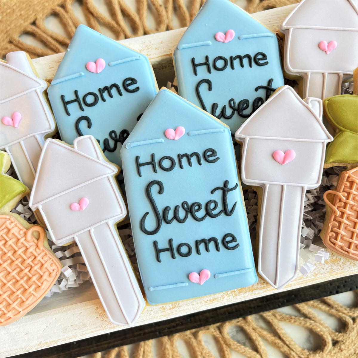 Light blue and white house key shaped sugar cookies with home sweet home black icing and pink heart decorations for housewarming