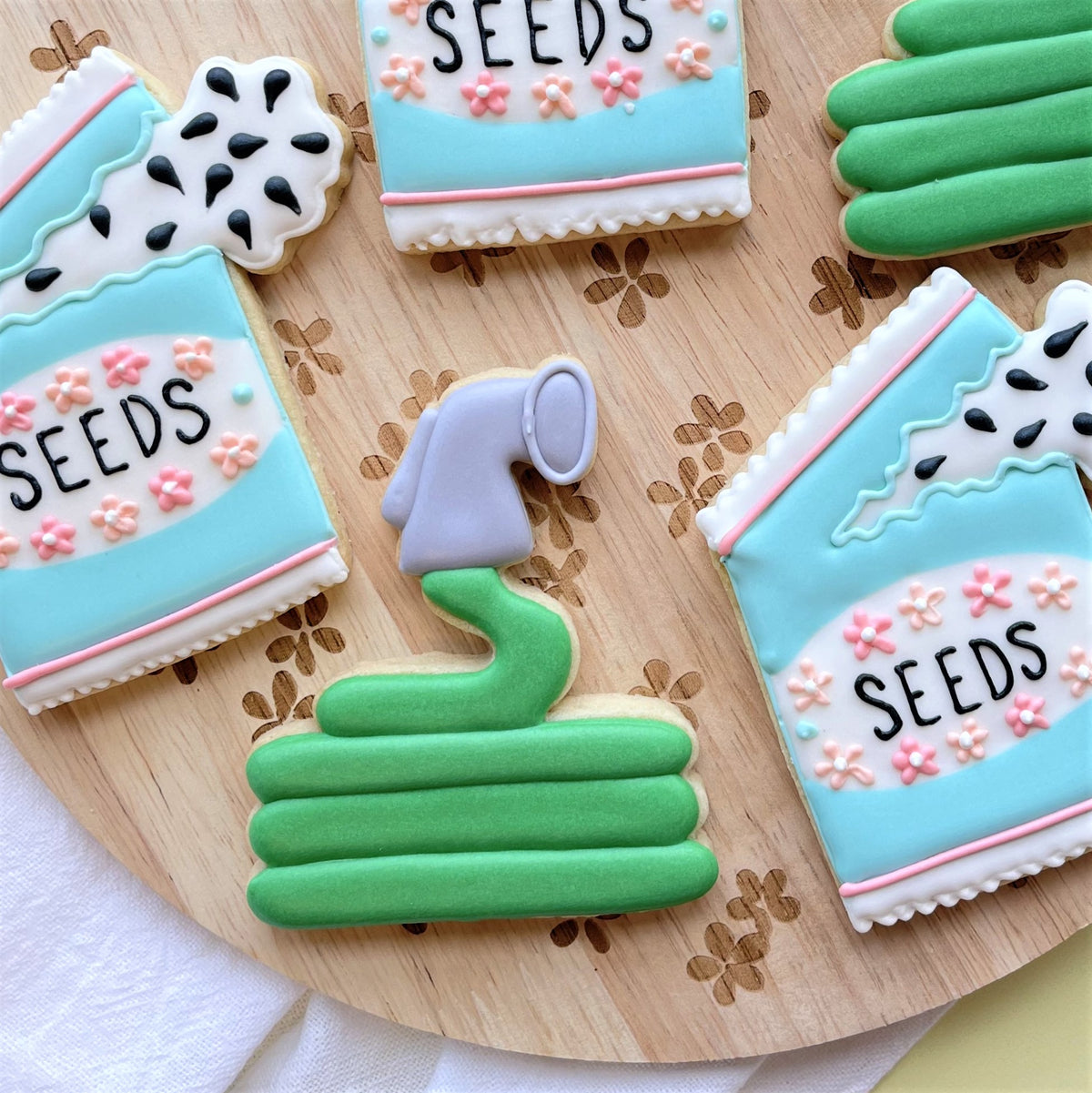 A whimsical green and gray garden hose cookie with purple nozzle decorated like an icing sugar cookie for gardening mothers day