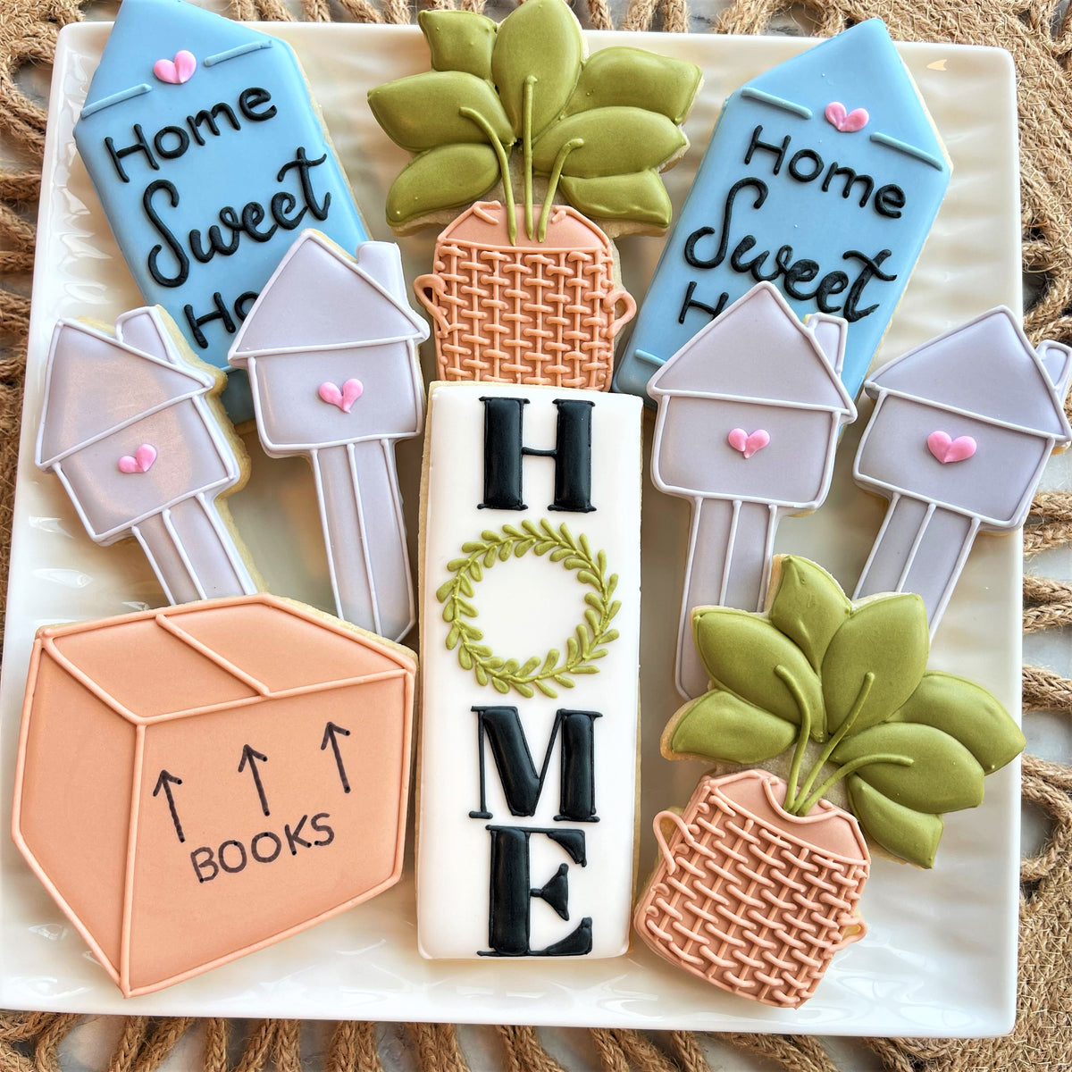 Rectangle tall cookie cutter shaped white cookie with black home lettering and green leaf wreath design in center