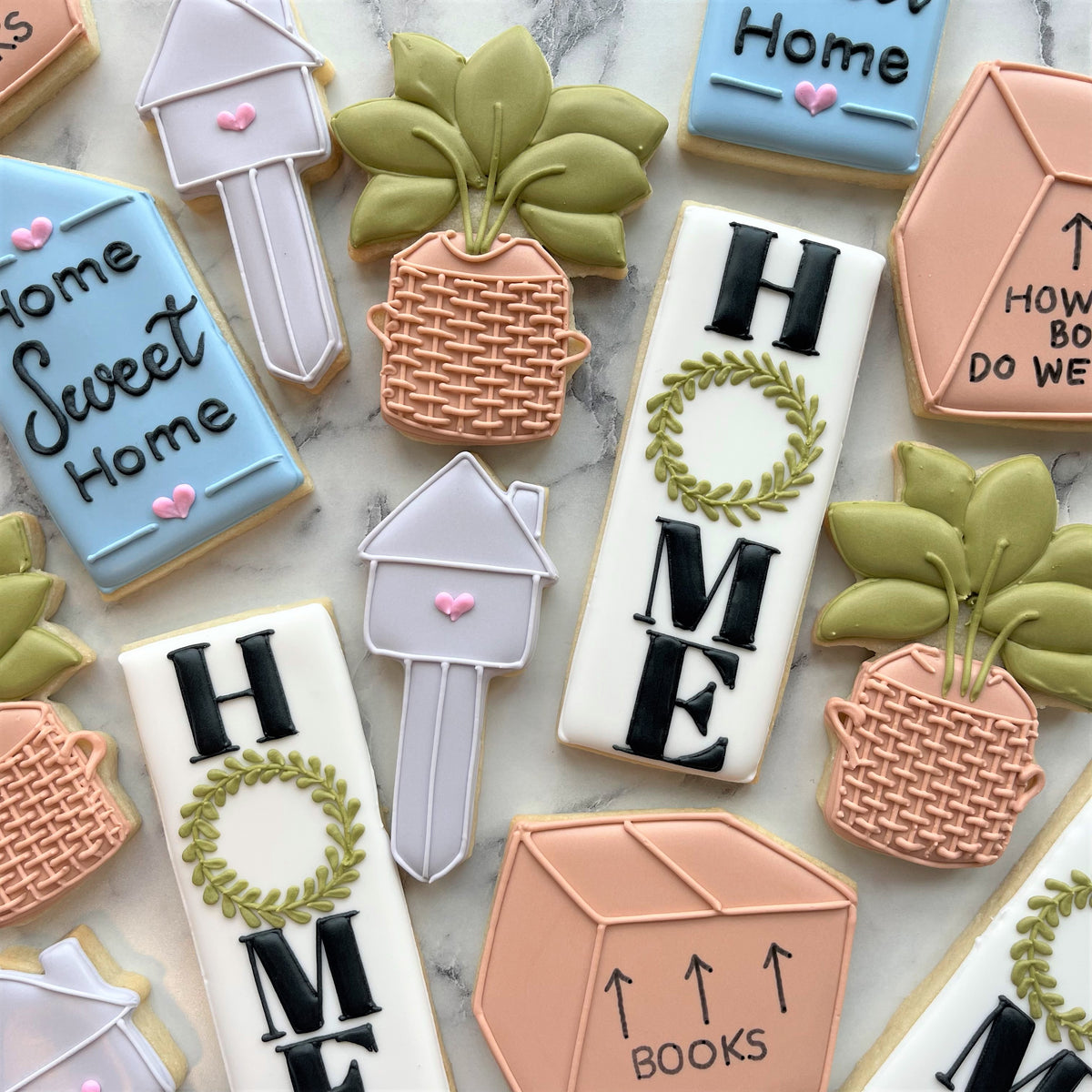 Pastel-colored sugar cookies shaped like house keys potted plants and home word with wreaths from housewarming cookie cutter set