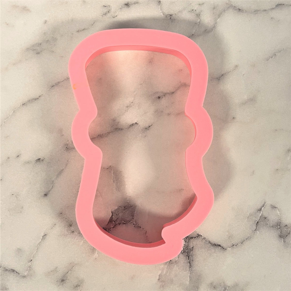 Pink silicone cookie cutter shaped like baby onesie designed for grad diploma rolled cookies