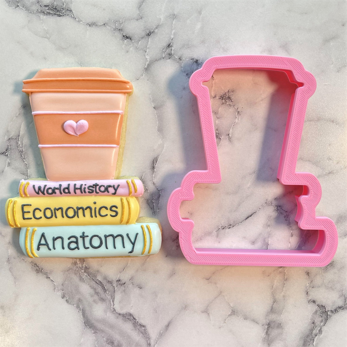 Pink plastic cookie cutter shaped like a coffee cup with lid and heart detail from latte on books collection