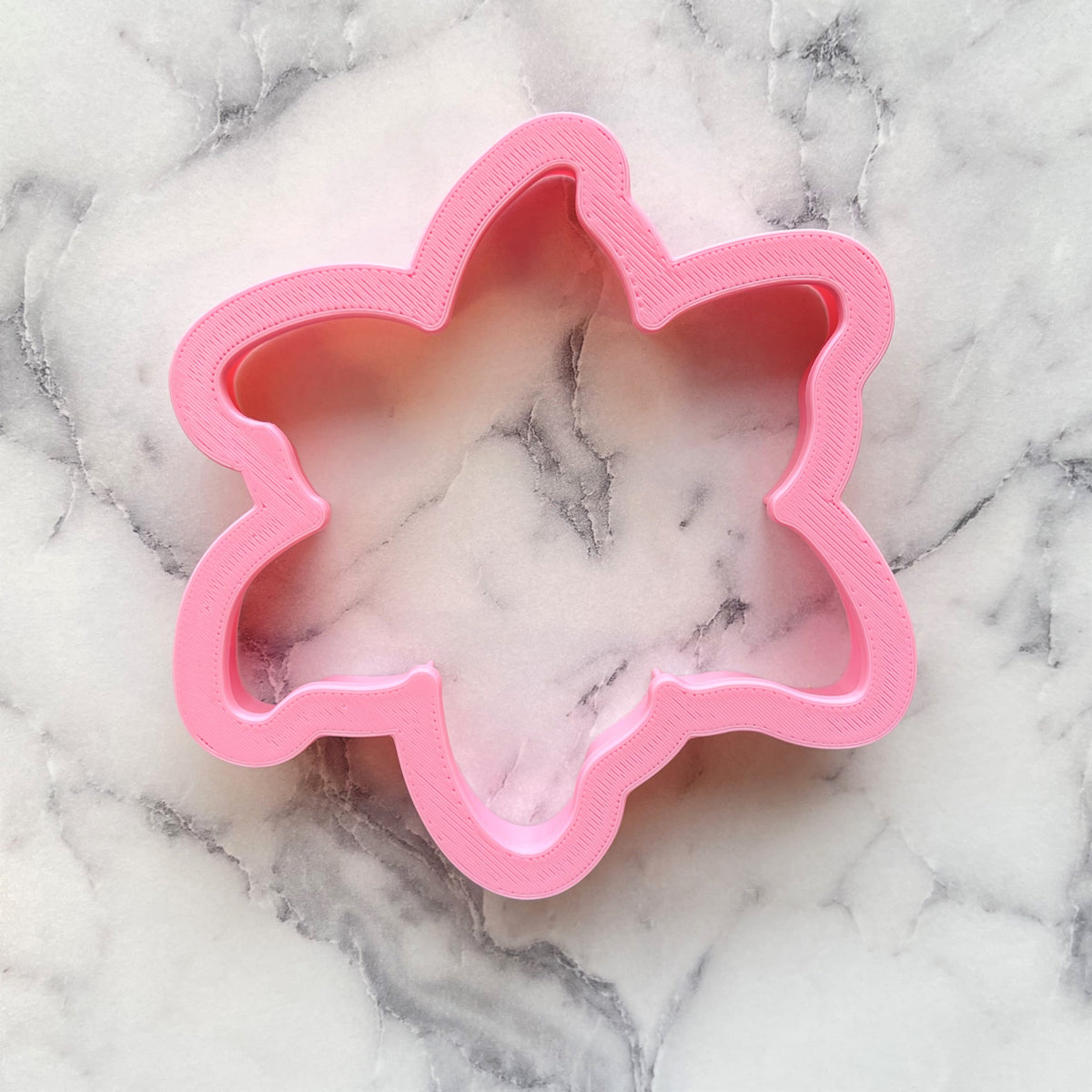 Pink plastic flower-shaped lily cookie cutter perfect for baking and decorating floral cookies
