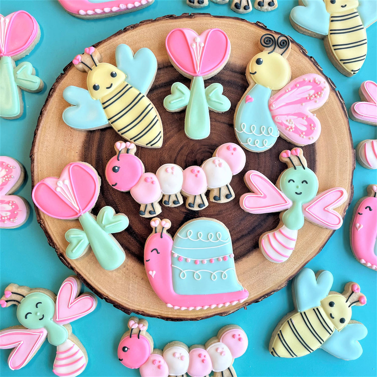 Pastel-colored sugar cookies shaped like bees butterflies caterpillars and snails made with lovebug cookie cutter set