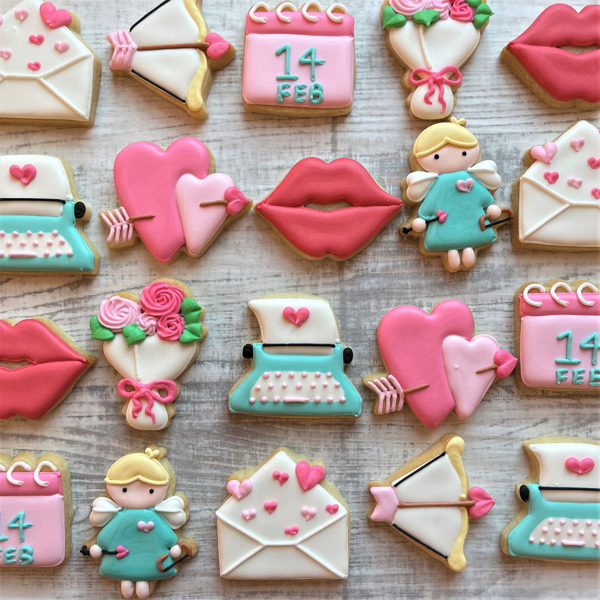 Pink and white iced valentine themed sugar cookies shaped like hearts lips envelopes calendar bows and arrows roses and angels made with mini calendar cookie cutter