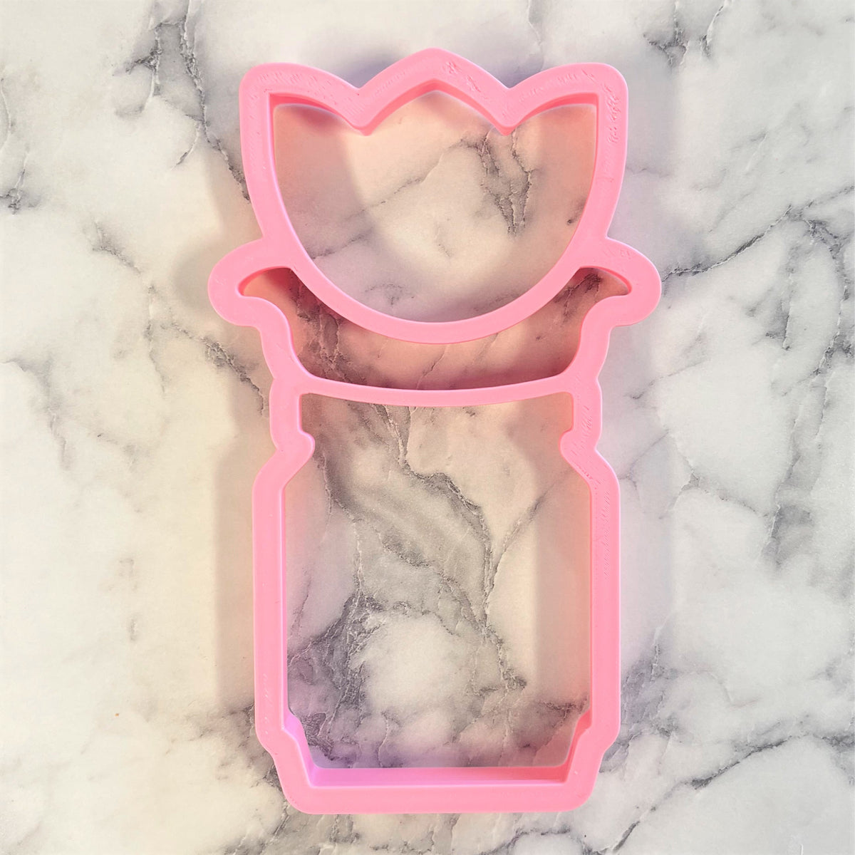 Pink silicone tulip-shaped mold inside a mason jar cookie cutter for flower-themed baking crafts