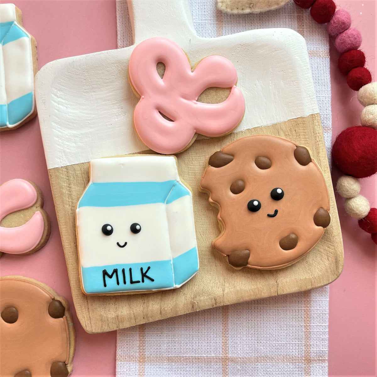 A chocolate chip cookie cutter shaped cookie decorated like a milk carton with white and light blue icing and black candy eyes