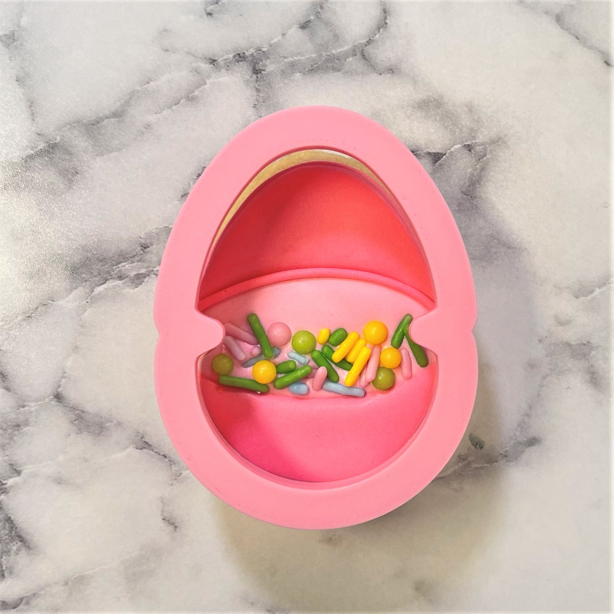 Pink silicone mini easter egg baking mold filled with colorful candy sprinkles for candy cookie cutter use