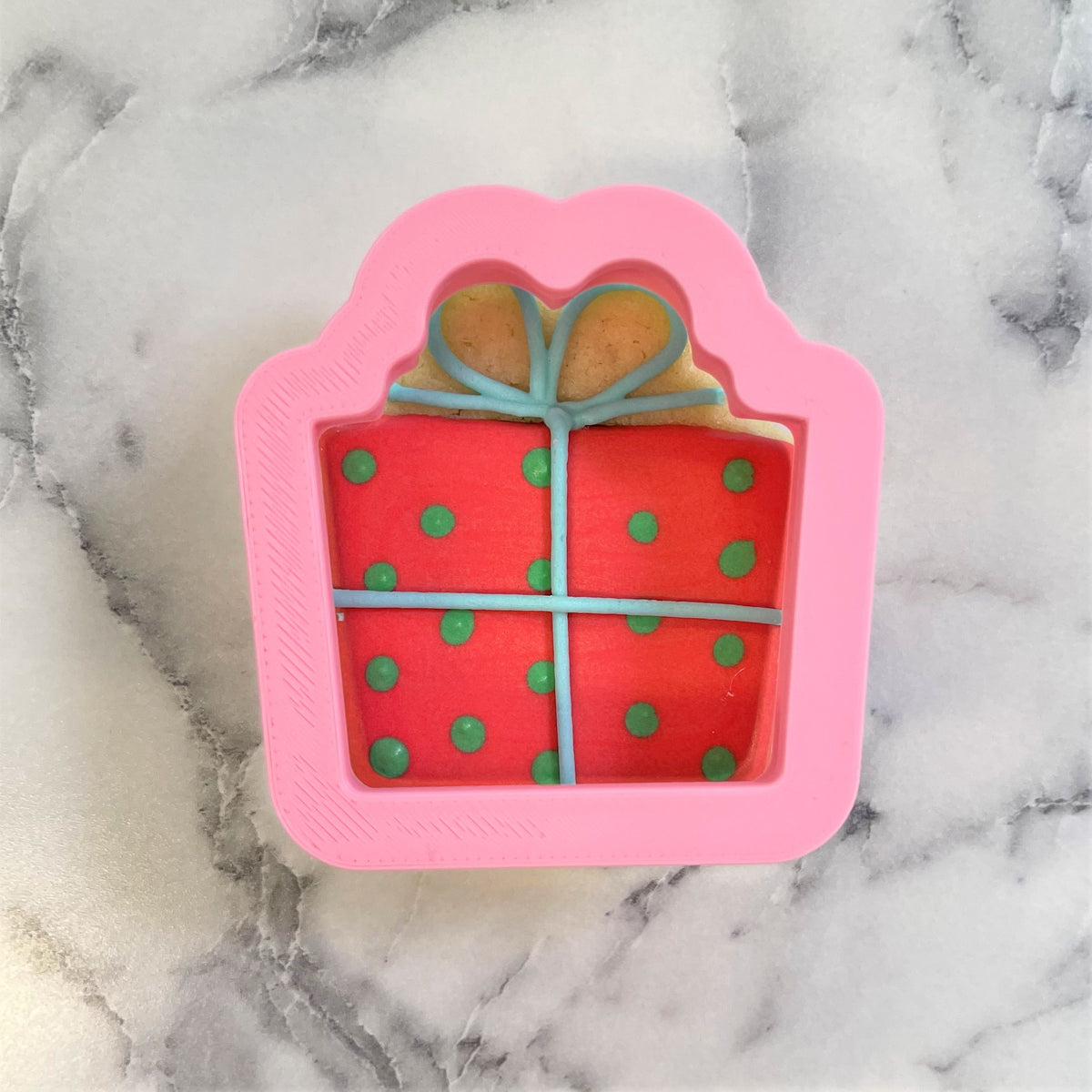 Mini classic present cookie cutter made of pink silicone with red interior green polka dots and light blue ribbon details