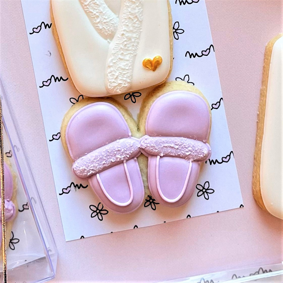 Pastel pink mini slippers cookie cutter cookies with white icing trim and glittery textured band