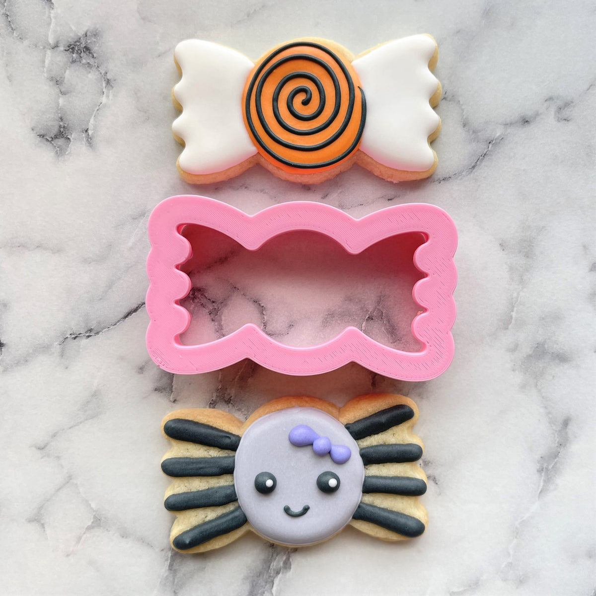 Mini candy wrapped cookie flip cutter in pink with scalloped edges designed for candy-shaped cookies