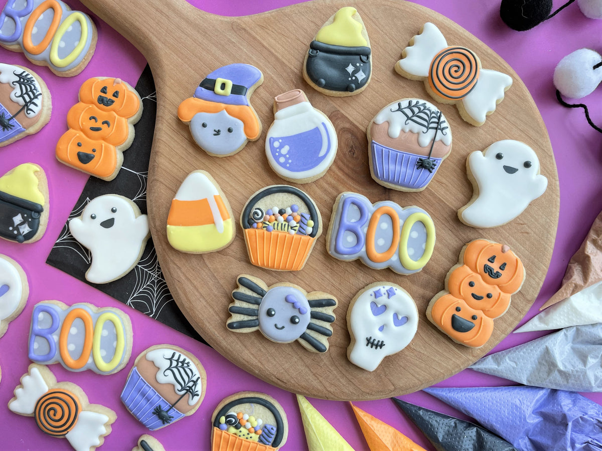 Mini ghost cookie flip cutter with halloween-themed sugar cookies decorated with orange purple and white icing