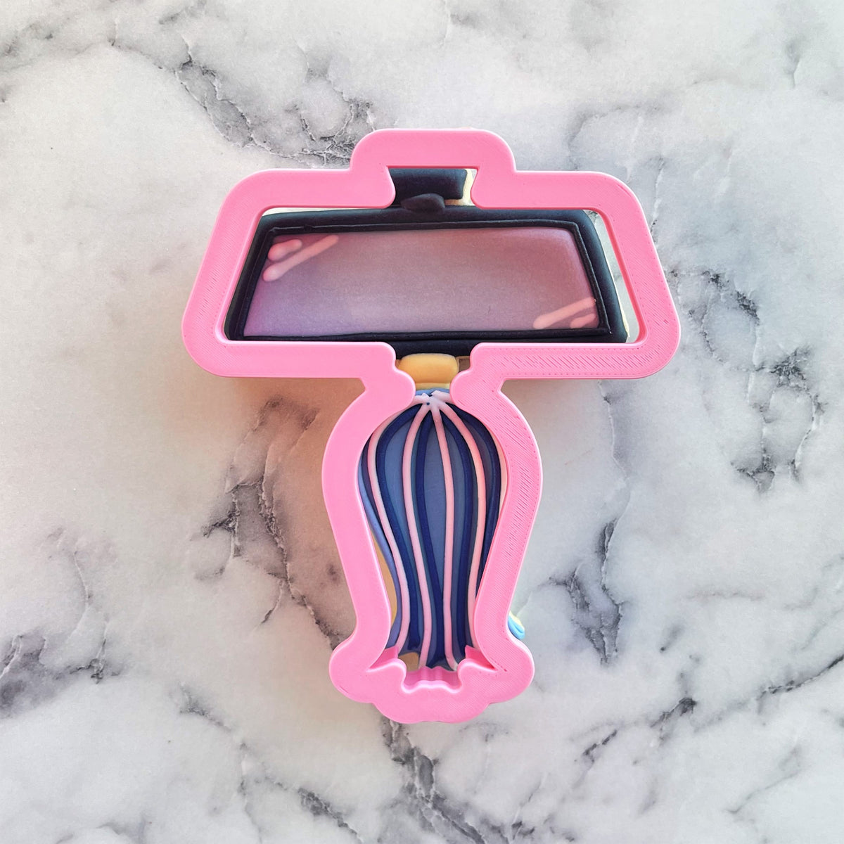 Pink 3d-printed rearview mirror and tassel cookie cutter with black top and blue-and-white striped base