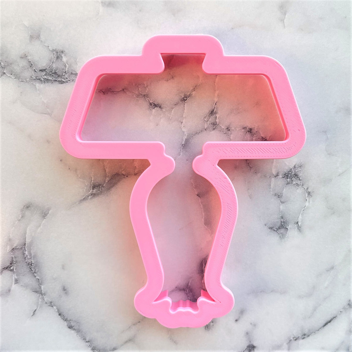 Pink plastic cookie cutter shaped like a table lamp from rearview mirror and tassel cookie cutter set