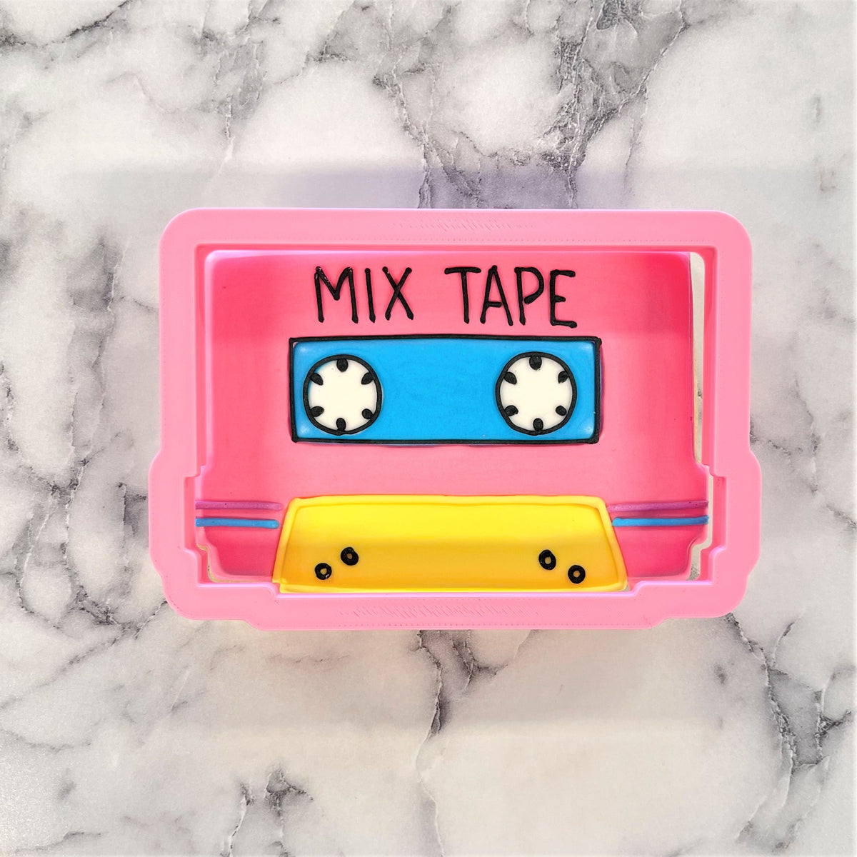 Pink silicone mix tape cookie cutter with blue and yellow accents for baking and crafting projects