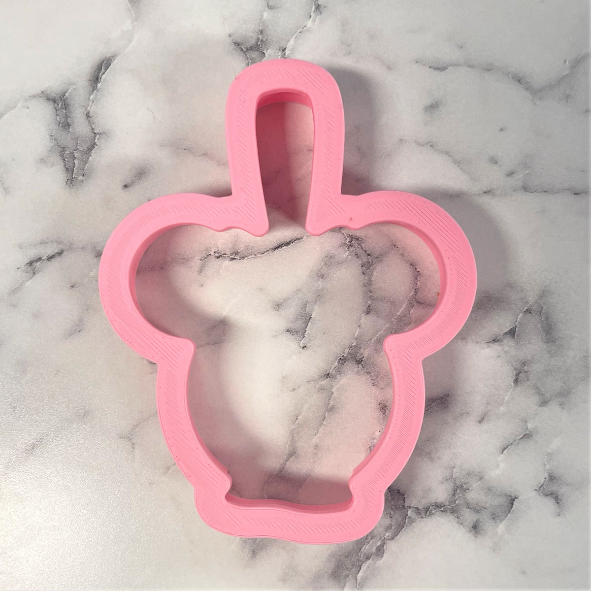 Pink plastic mouse candy apple cookie cutter shaped like a cupcake with handle for baking and decorating