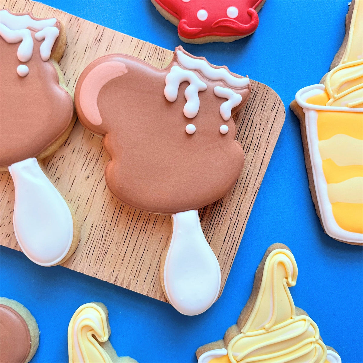 Chocolate-frosted cookie shaped like a soft-serve ice cream cone with white icing drips and spoon handle from mouse snacks cutter bundle