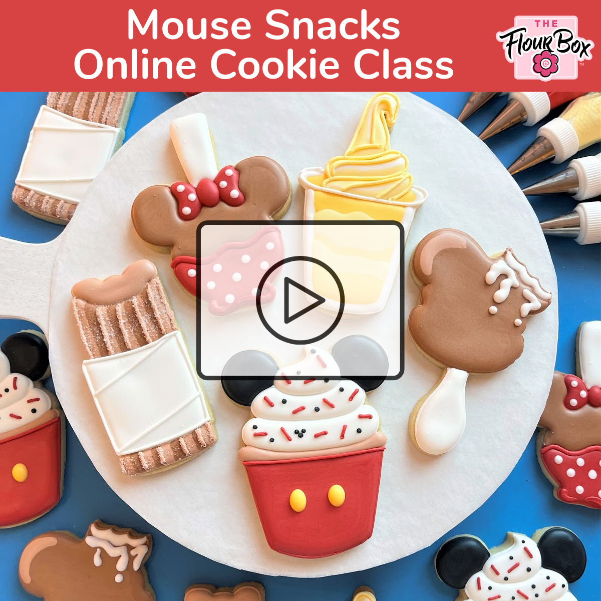 A red cupcake-shaped cookie with white frosting colorful sprinkles and two yellow buttons from mouse snacks online cookie decorating class recording