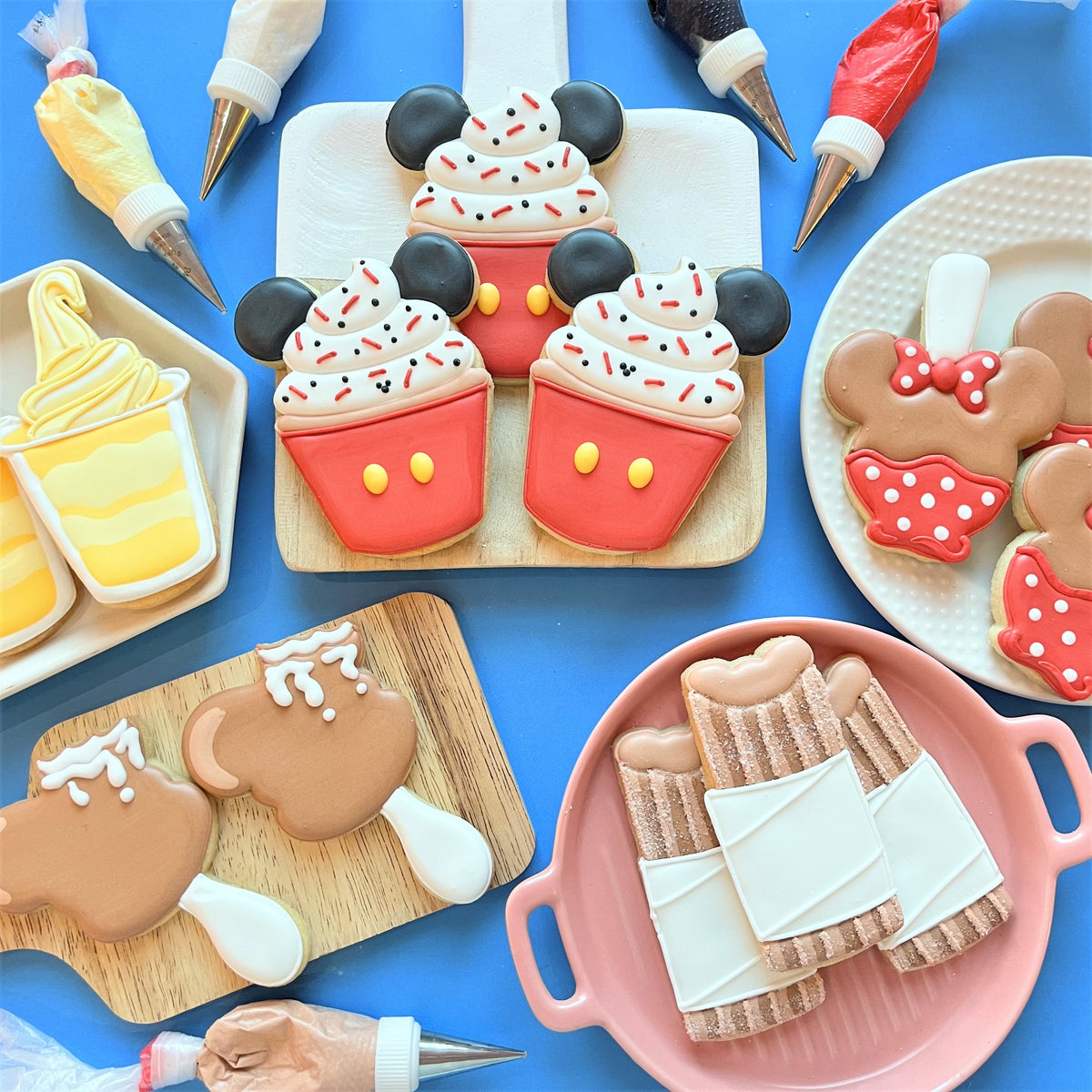 Red mickey mouse-themed churro cookie cutter with white frosting black ears and yellow buttons on cupcake cookies
