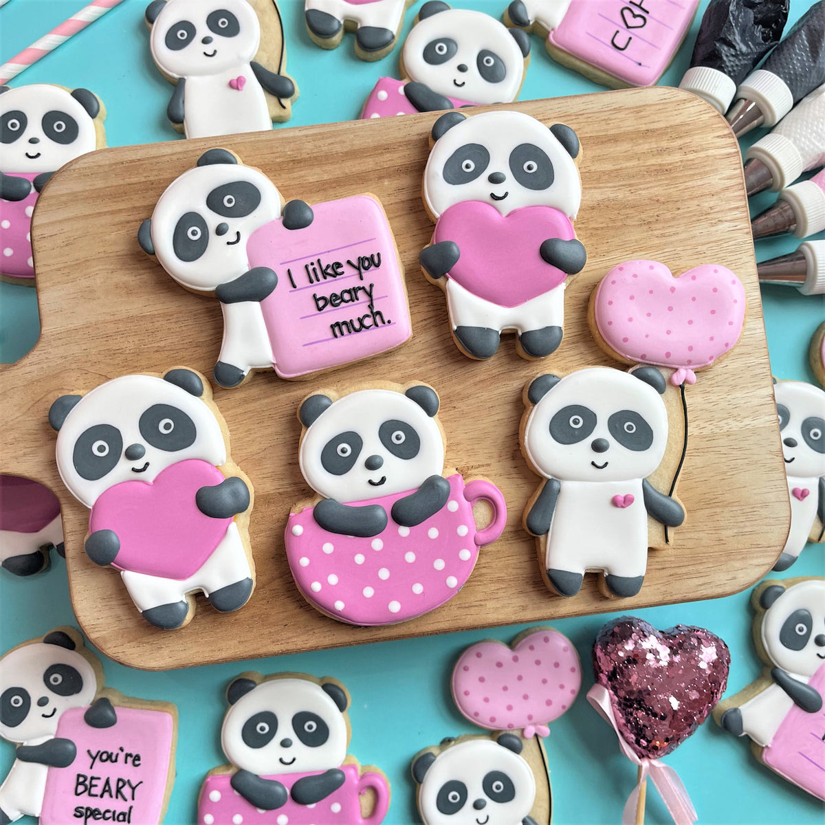 Pink frosted panda shaped cookies with black eyes ears holding hearts and i like you beary much sign made with panda balloon cookie cutter