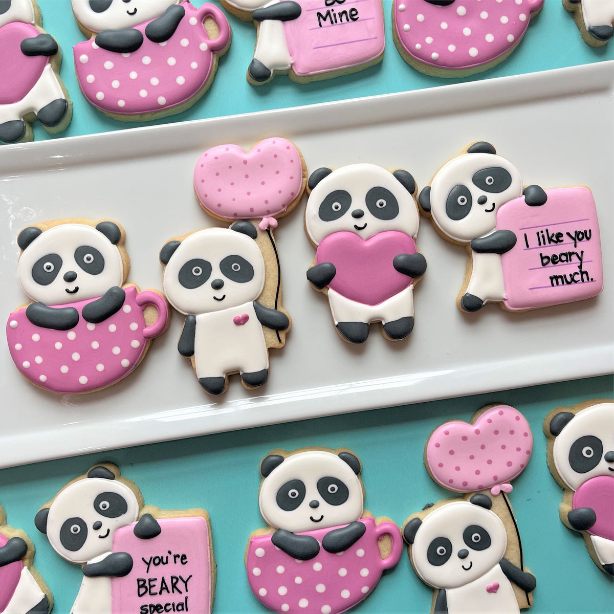 Pink polka-dotted panda shaped cookies with white icing faces and black details made using panda with balloon cookie cutter