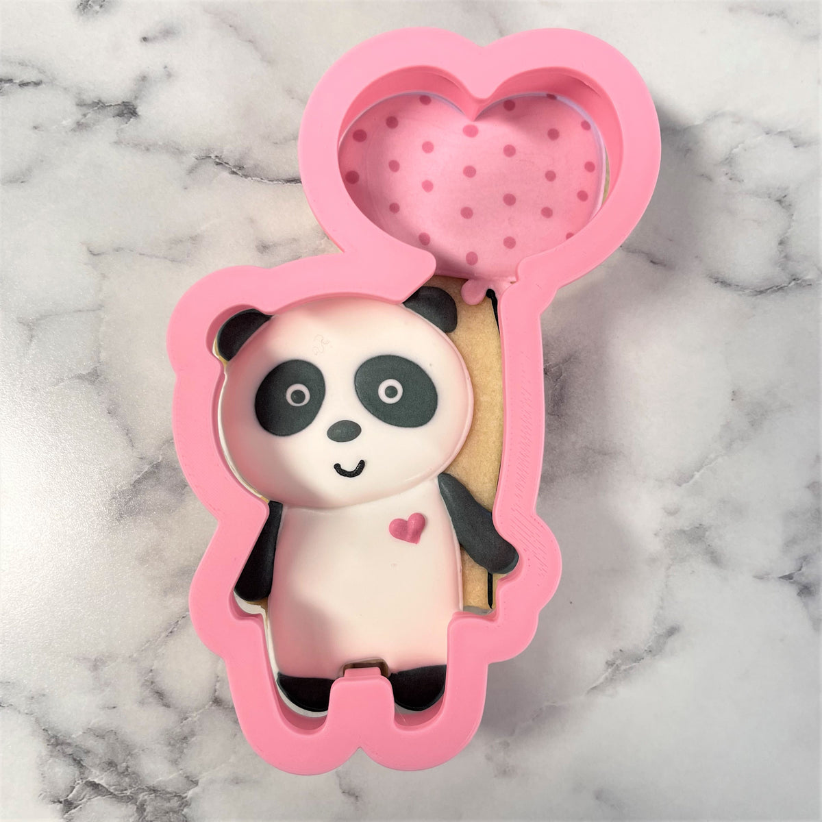 Pink silicone panda shaped cookie cutter with heart balloon design and polka dot interior for baking use