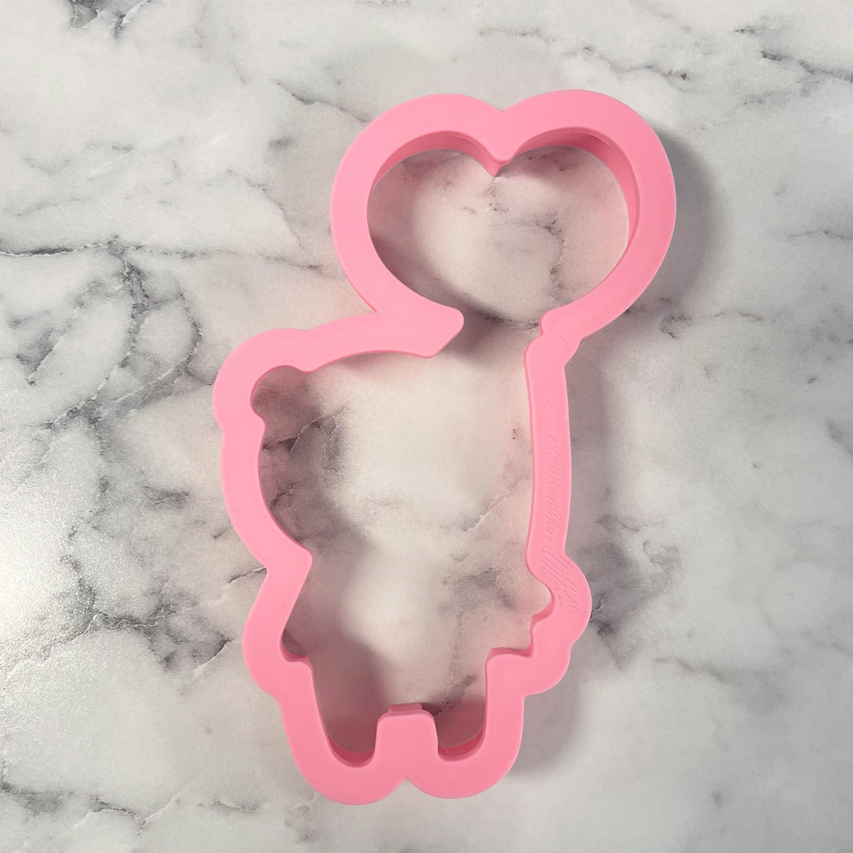 Pink silicone mold shaped like a panda with balloon cookie cutter featuring a heart shaped head and dress