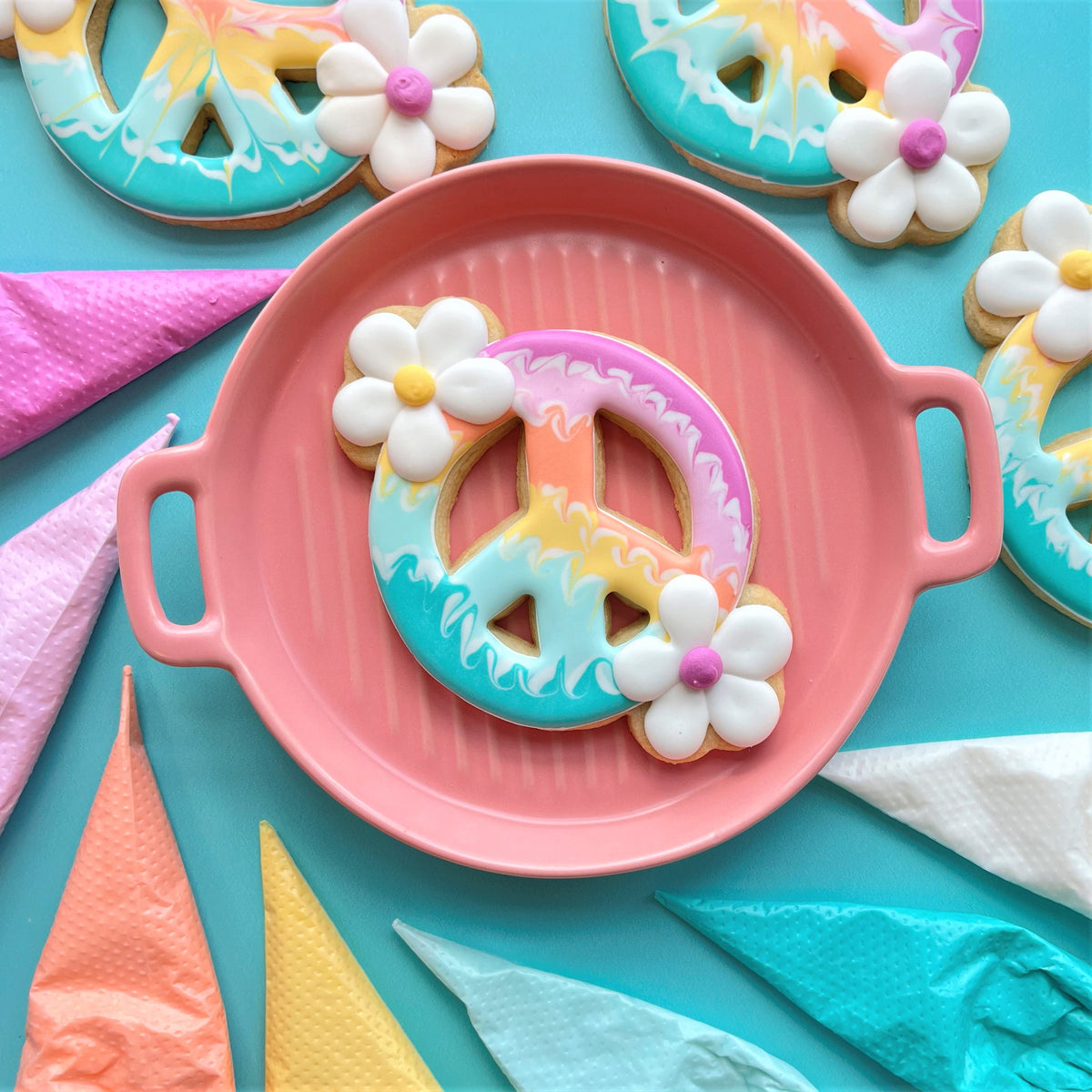 Pastel tie dye peace sign cookie with white flowers on coral ceramic plate from groovy 5 cutter bundle and guide