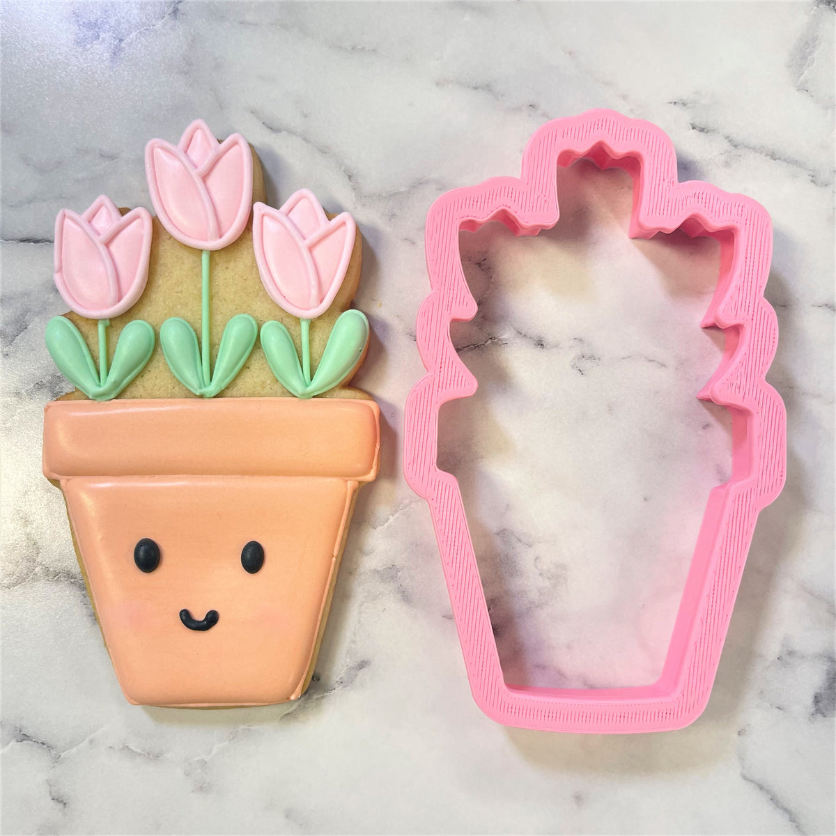 A pink plastic potted tulips cookie cutter shaped like a flower pot with decorative ridges on its sides