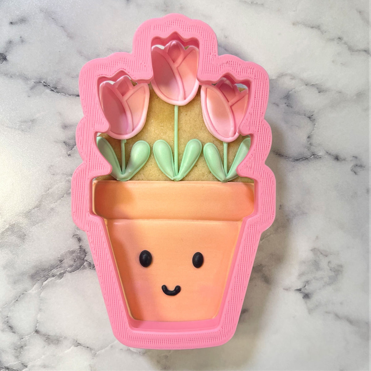 Pink tulip pot cookie cutter with smiling face and green leaves for baking potted tulip shaped cookies