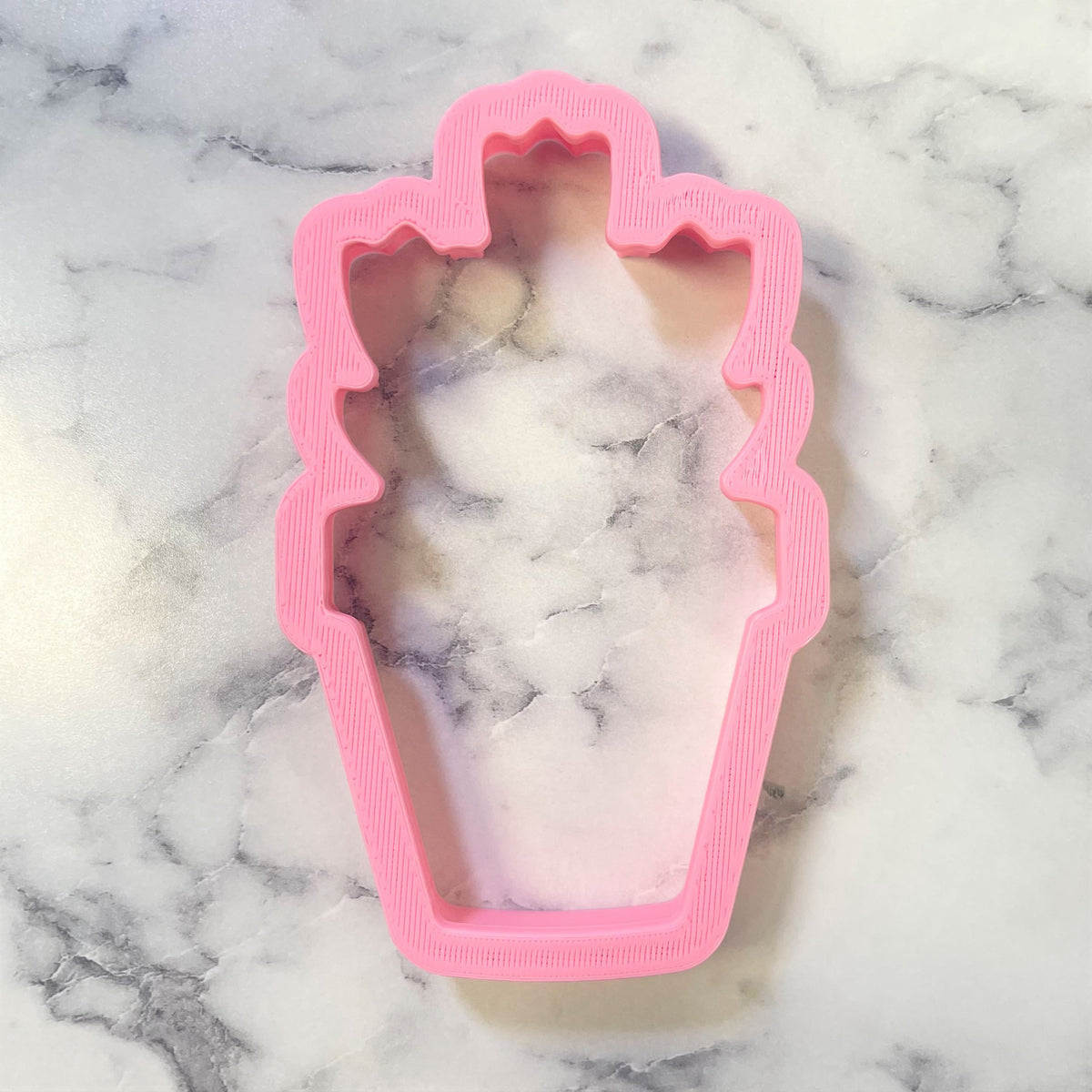 Pink plastic coffin-shaped cookie cutter with marbled interior for potted tulips themed baking crafts