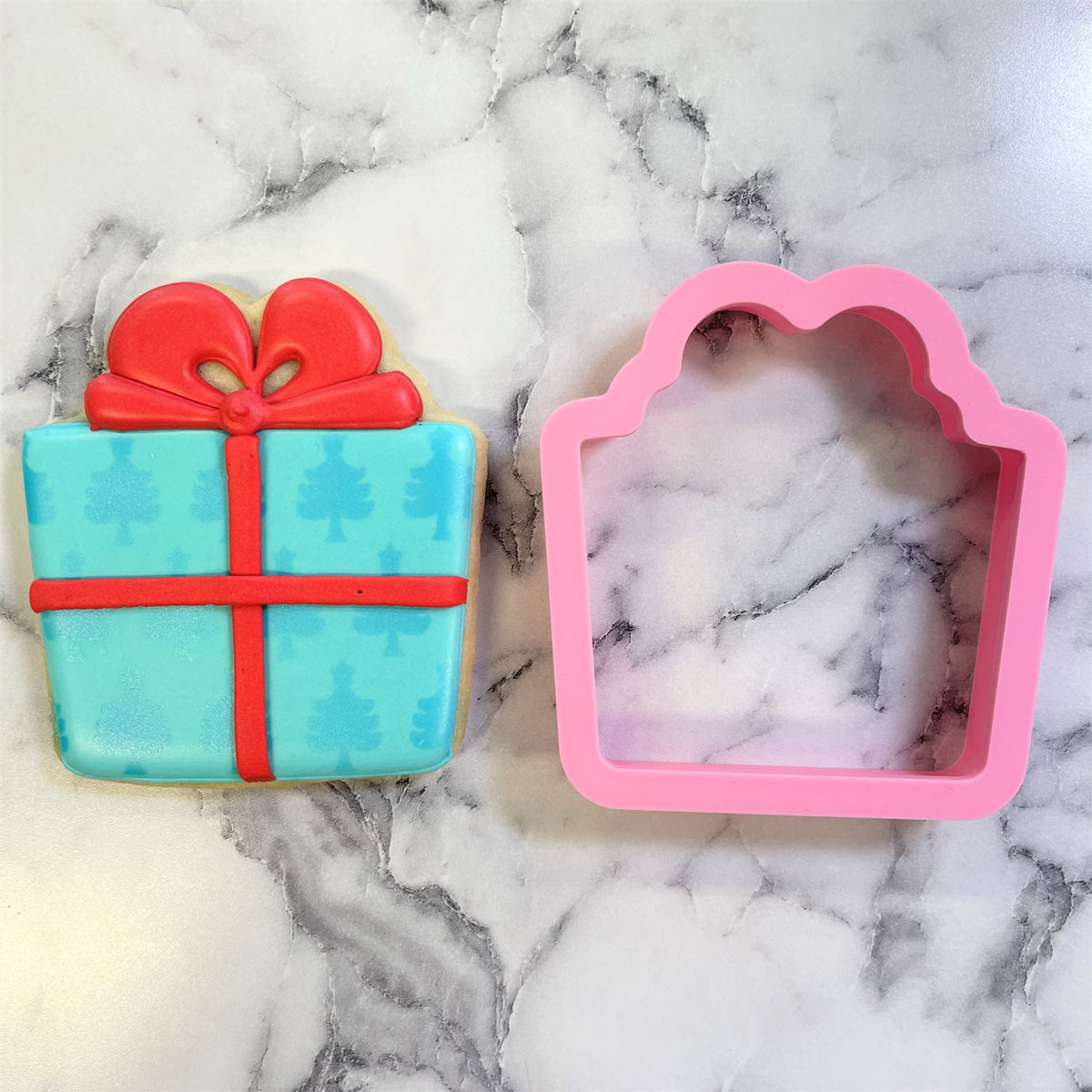 A pink silicone classic present cookie cutter with a scalloped top edge for gift box shaped cookies