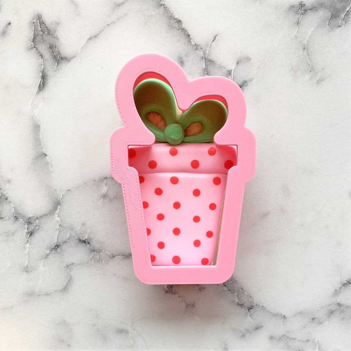 Present with bow small cookie cutter is a pink metal gift box shape with red polka dots and a green bow on top